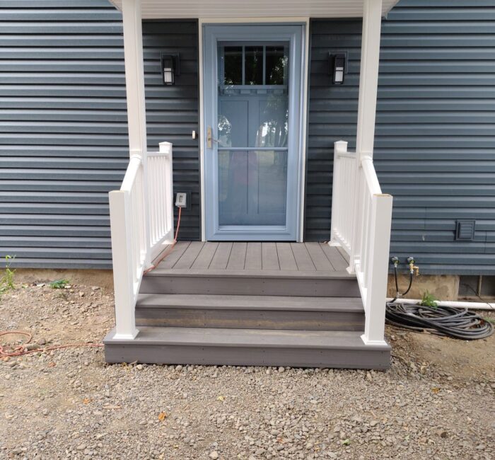 Front porch with new white railings, new storm door, and new door installed by Bauer Specialty